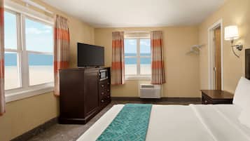A hotel room with a bed, a TV, a dresser, and a window with curtains.