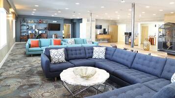 A modern living room with a sectional sofa, a round coffee table, and a television mounted on the wall.