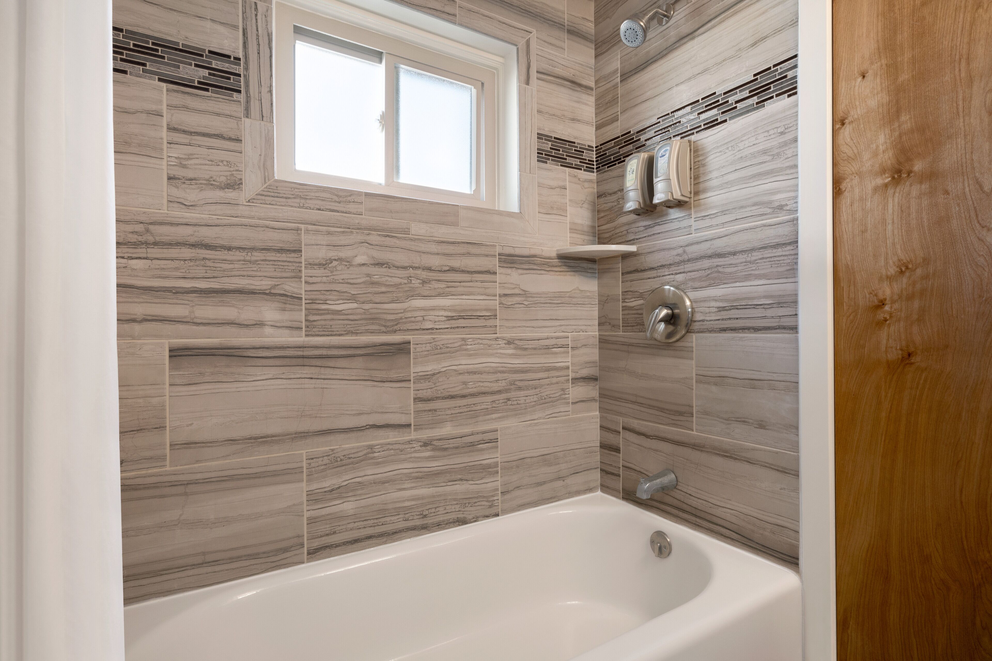 A bathroom with a bathtub, a window, and a shower area.