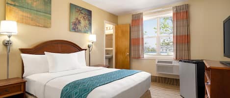 Une chambre d’hôtel avec un lit, des lampes de chevet, un bureau, une télévision et une fenêtre avec des rideaux.