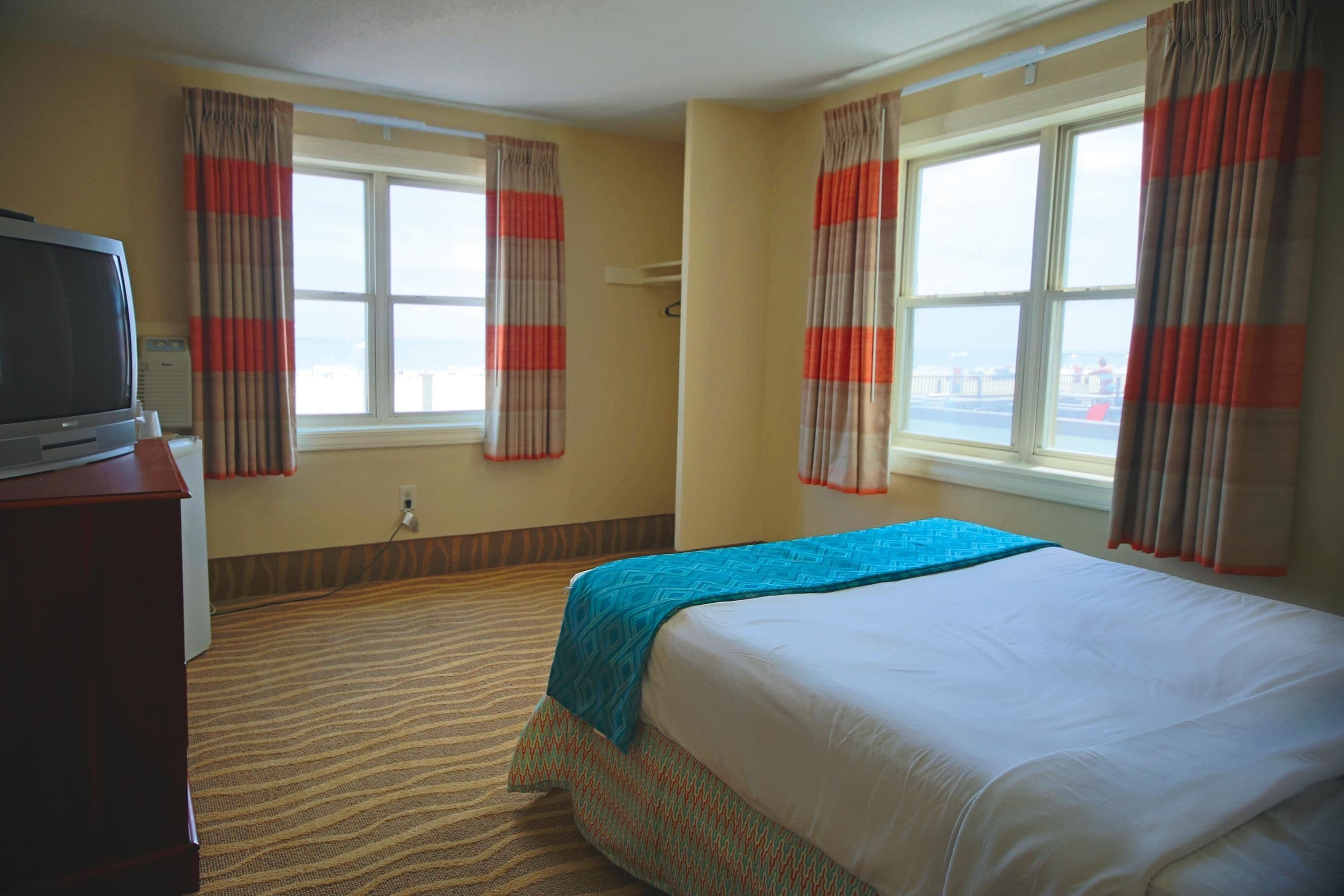 Une chambre d’hôtel avec un lit, une télévision et une fenêtre avec des rideaux.