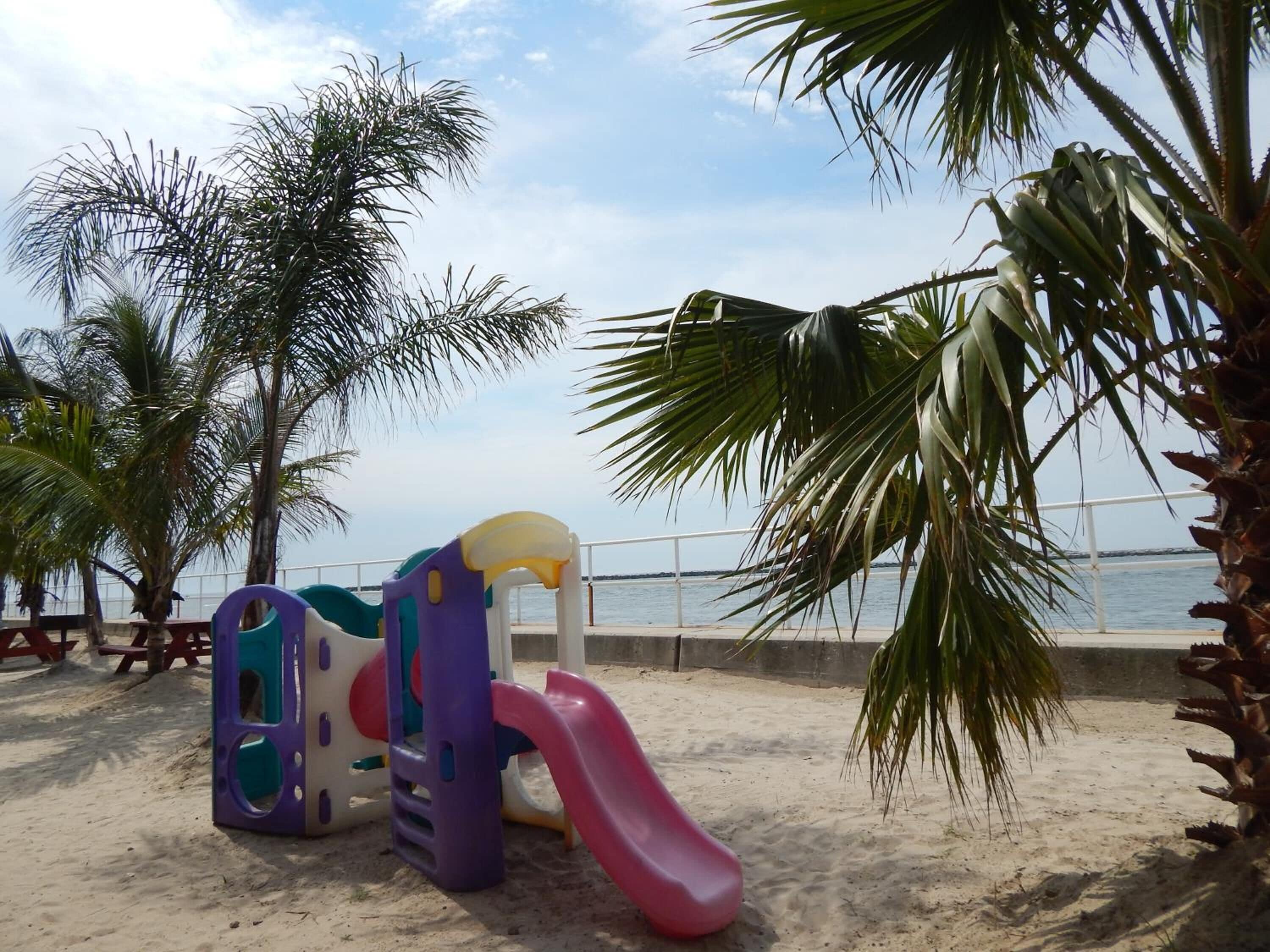 Un parque infantil en la playa con un tobogán y estructuras para escalar.