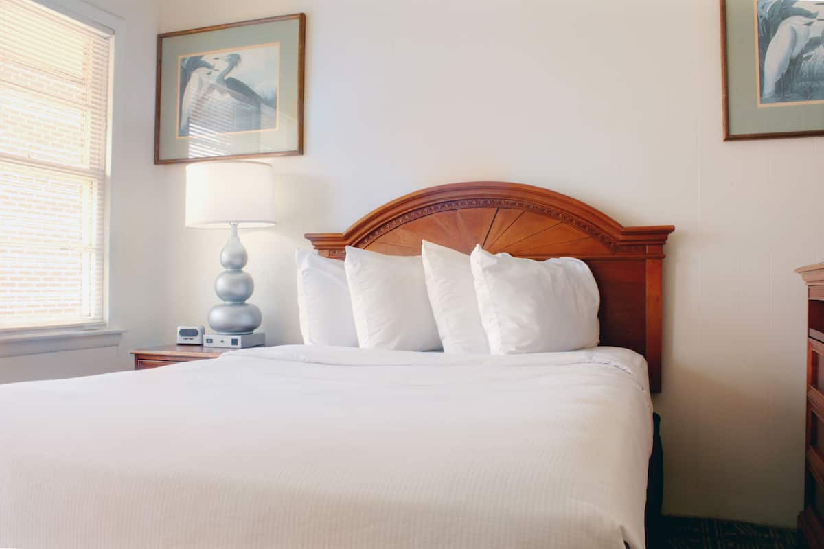 A neatly made bed with a wooden headboard, a bedside lamp, and two framed pictures on the wall.