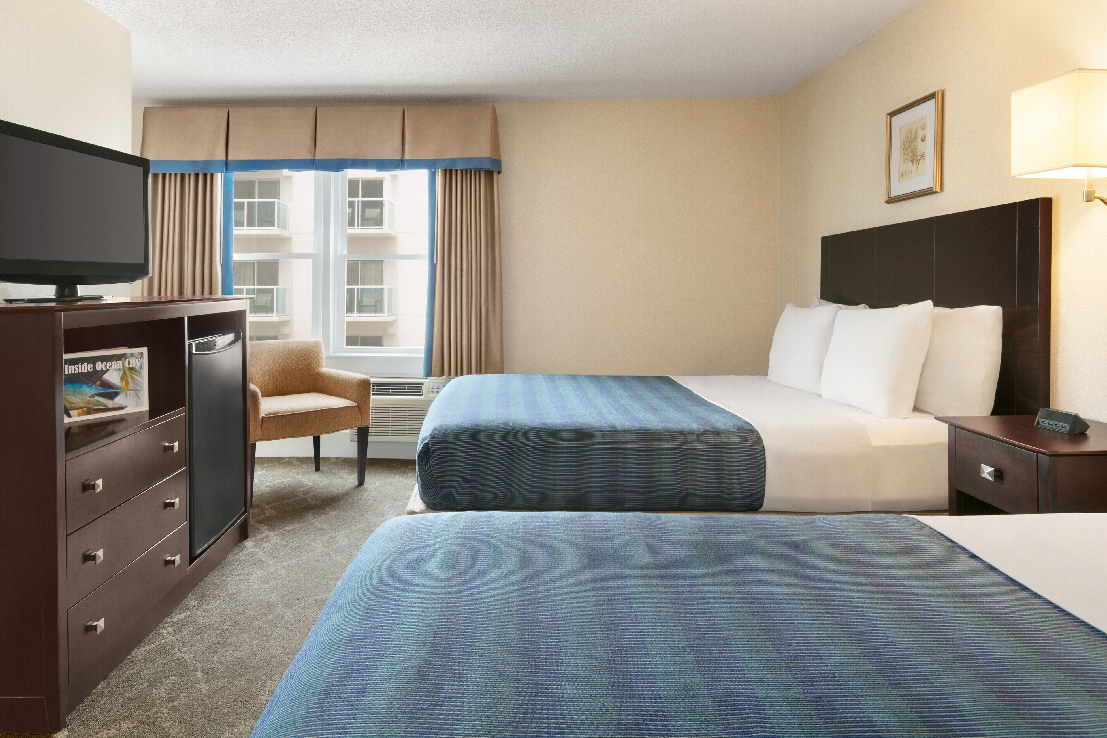 Une chambre d’hôtel avec deux lits, une télévision, un bureau et une chaise.