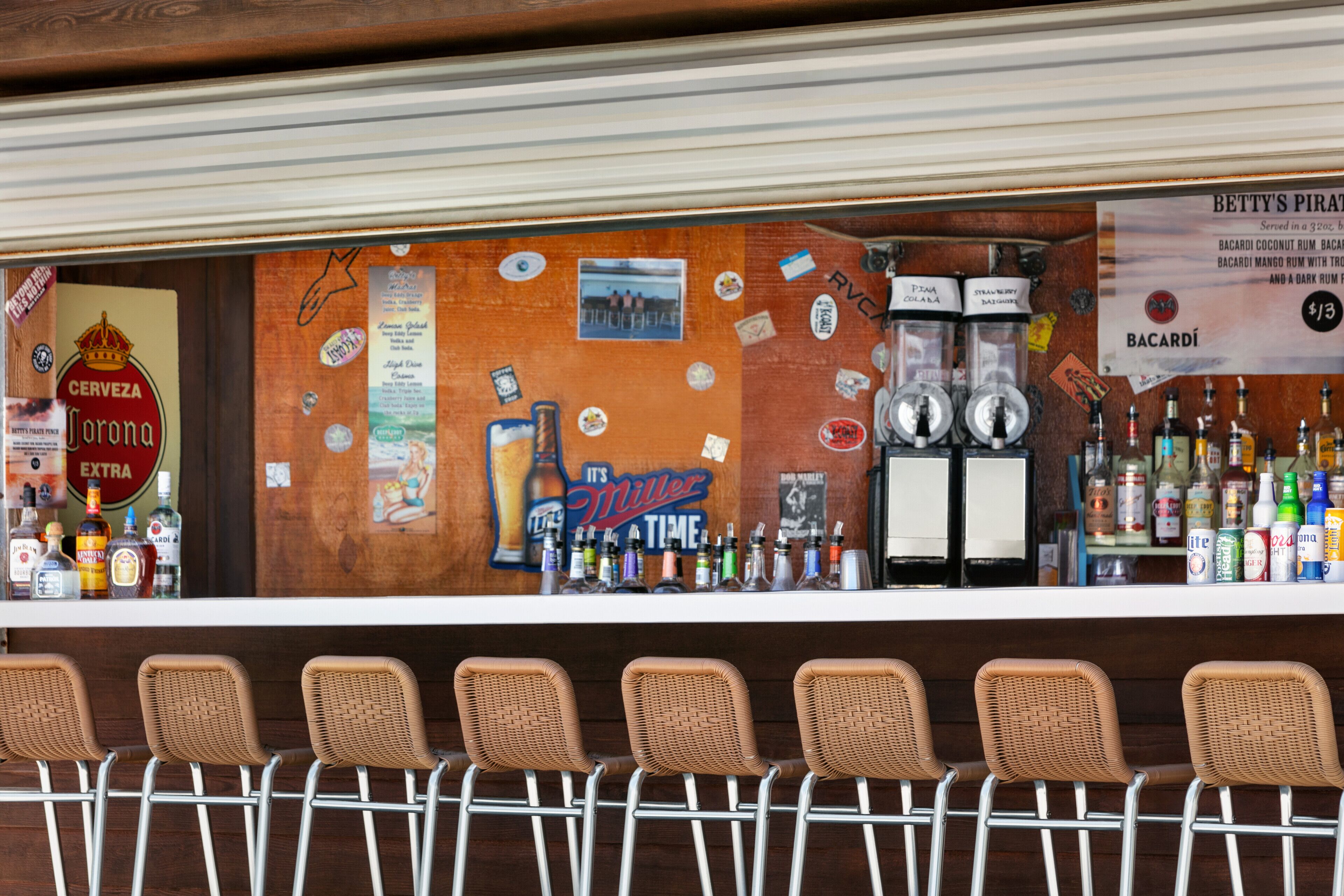 A bar area with a counter displaying various liquor bottles, a sign for Betty's Pirate, and a Miller Lite sign.