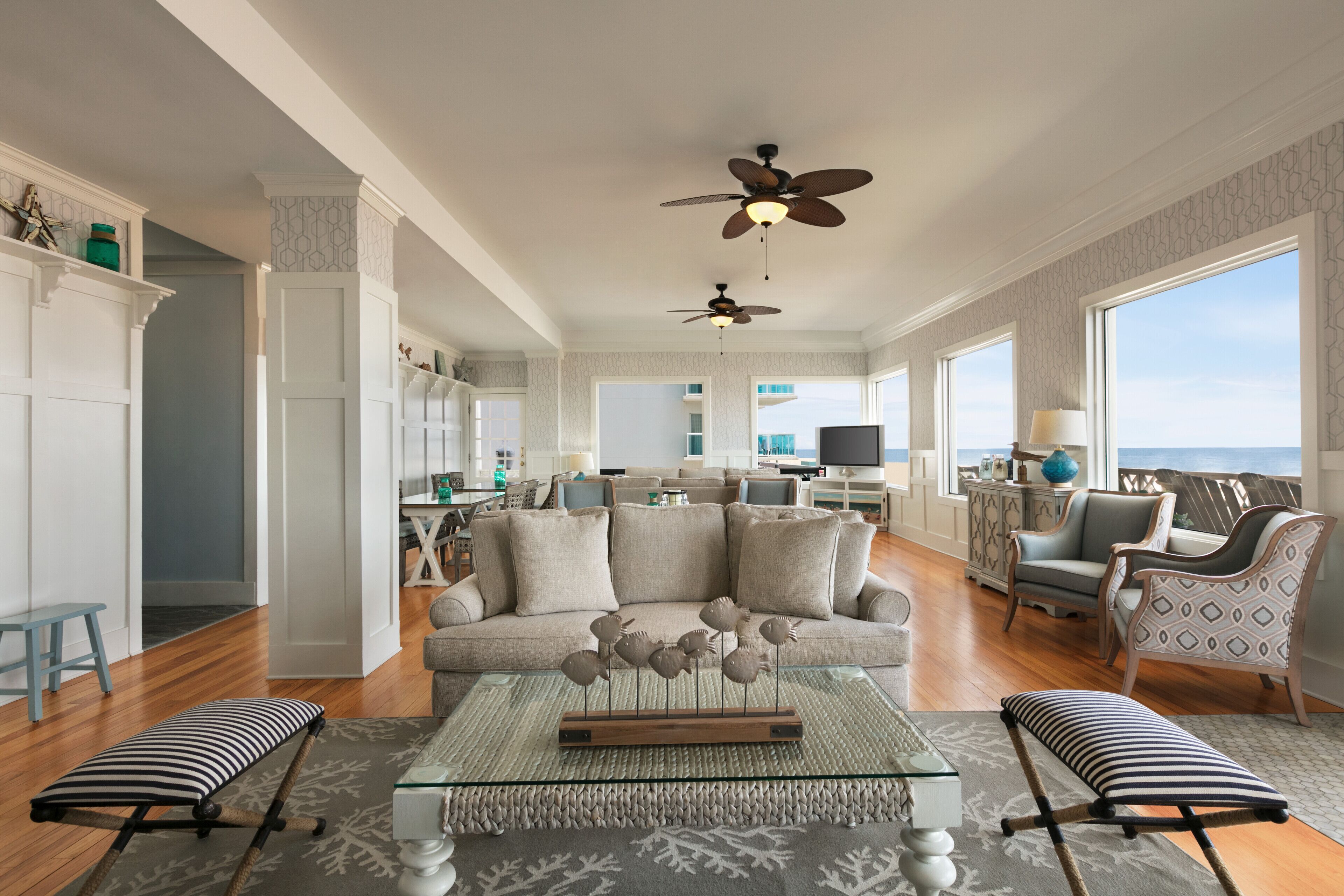 A spacious living room with a large sofa, a coffee table, and a view of the ocean.