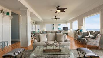 A spacious living room with a large sofa, a coffee table, and a view of the ocean.