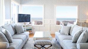 A living room with a large window, a flat-screen TV, and a sofa. - Harrison Hall Hotel (Ocean City)