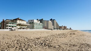 A beachfront hotel with multiple buildings, a sandy beach, and a clear blue sky. - Harrison Hall Hotel (Ocean City)