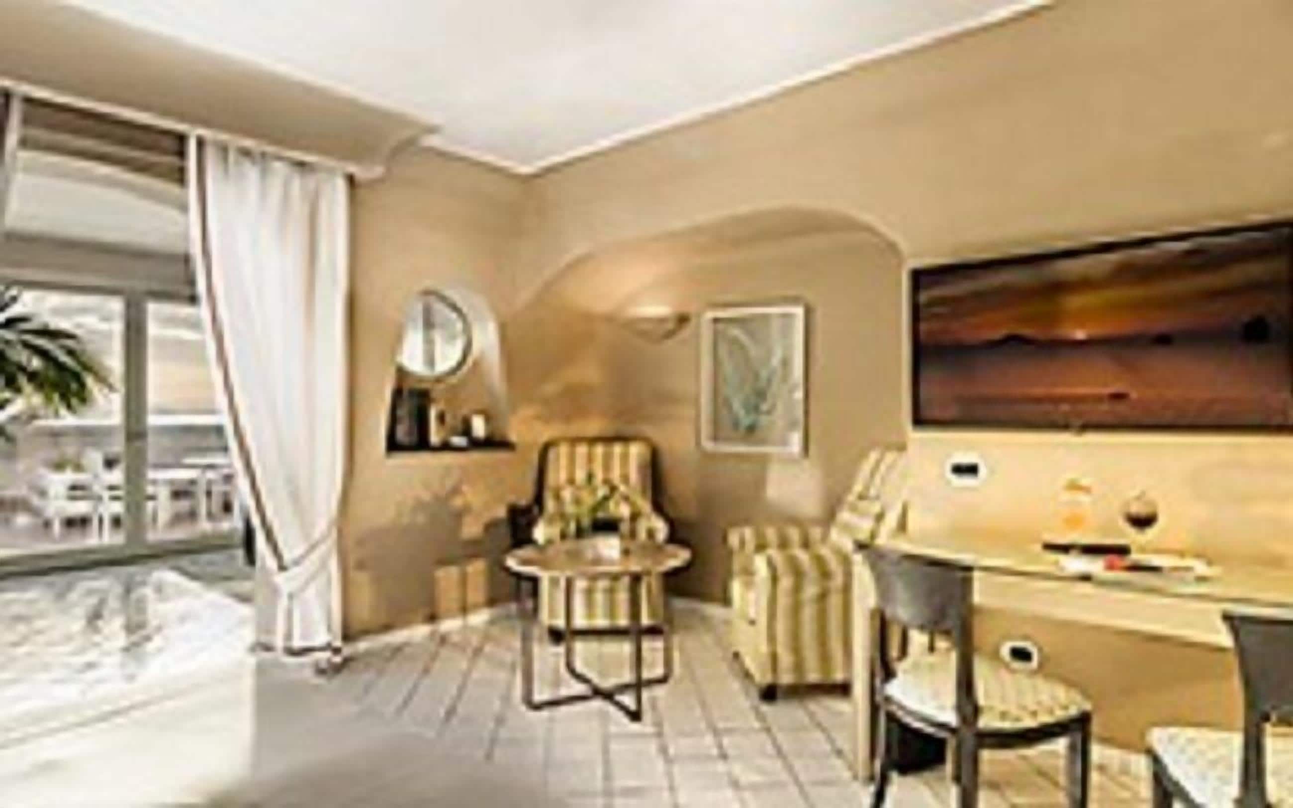 A modern hotel room with a large window, a dining area with a table and chairs, and a seating area with a sofa and armchairs.