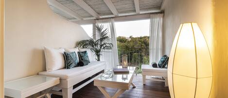 A balcony with a white sofa, a glass table, and a lamp.