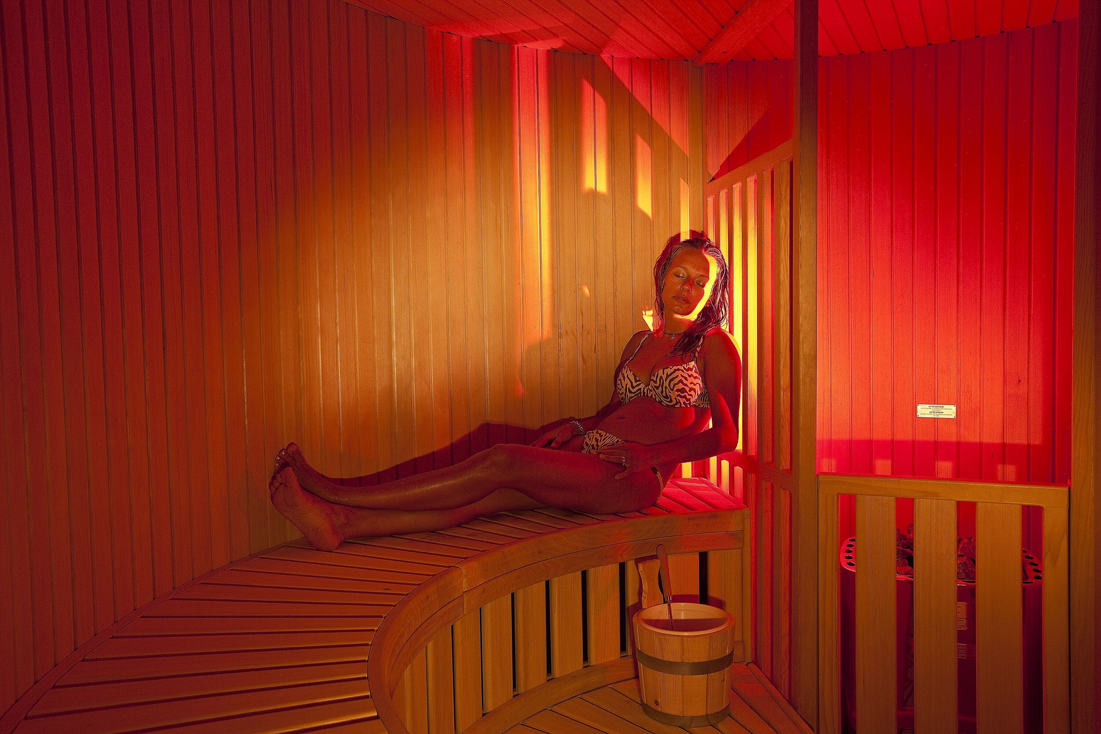 Una sauna con bancos de madera y un balde de madera.
