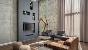 Een moderne woonkamer met een grote televisie, leren banken en een bakstenen muur.