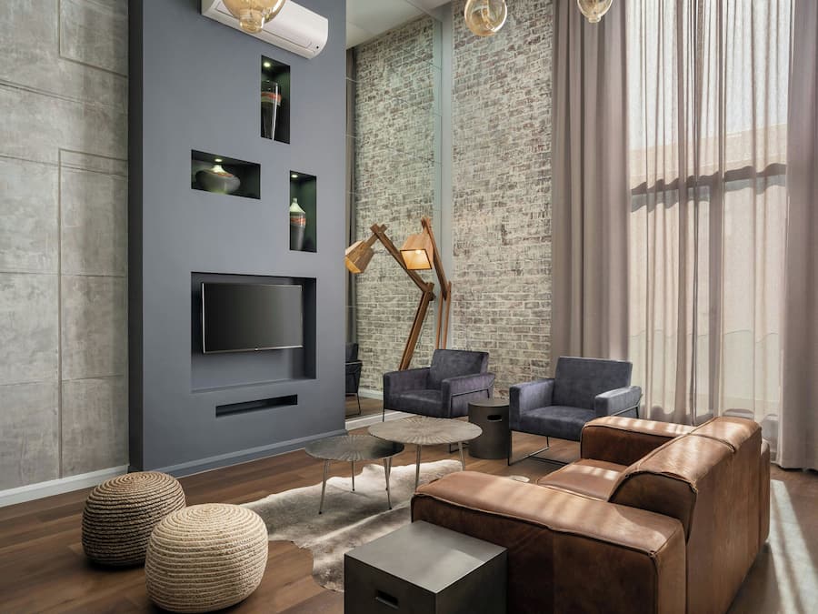 Uma sala de estar moderna com uma televisão grande, sofás de couro e uma parede de tijolos.