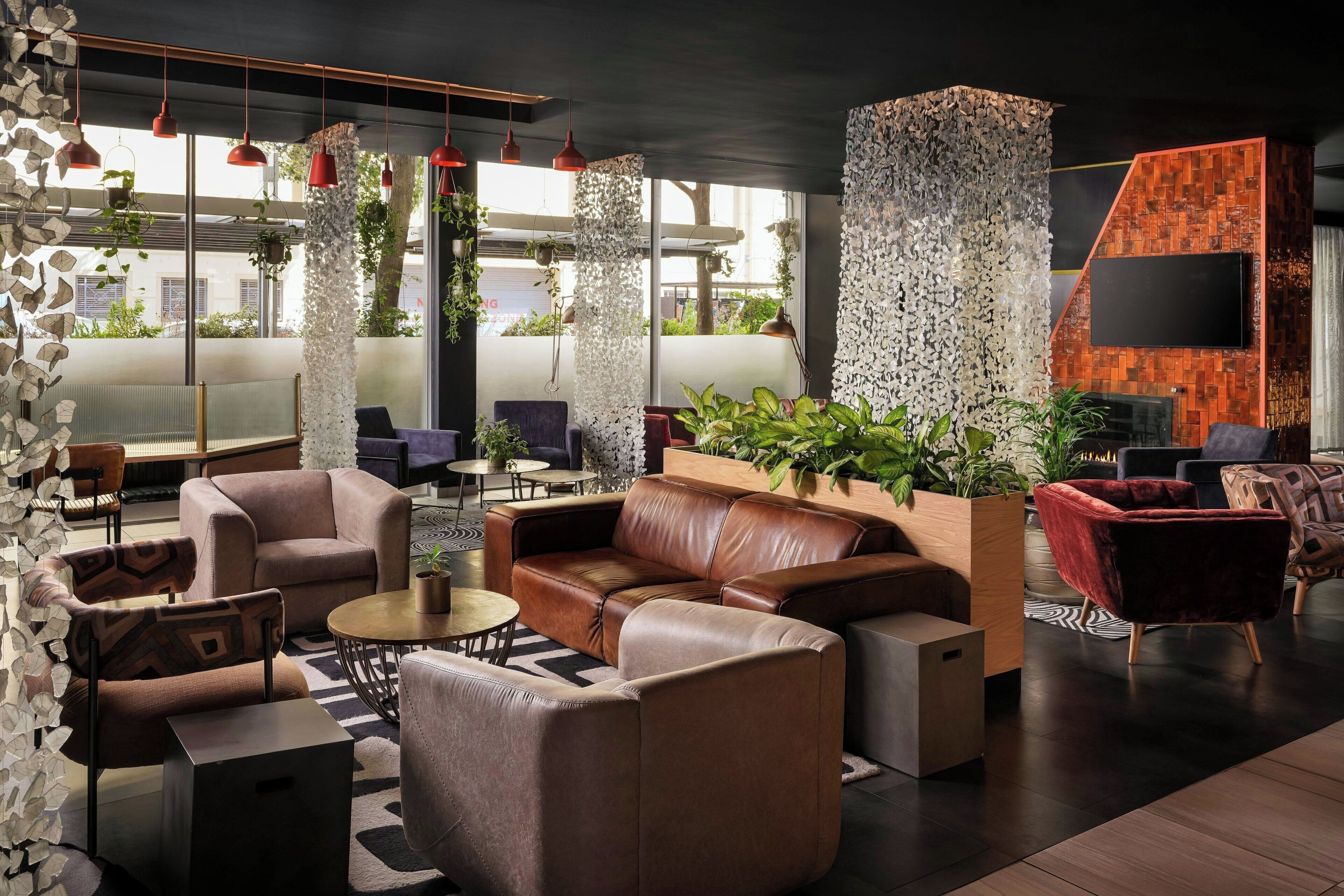 A modern lounge area with leather sofas, a coffee table, and hanging red pendant lights.