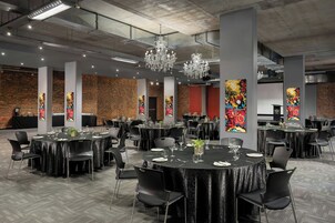 A conference room with round tables, black tablecloths, and modern chandeliers.