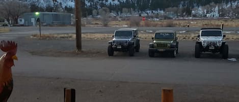 Three off-road vehicles parked on a dirt road with a stop sign in the background.