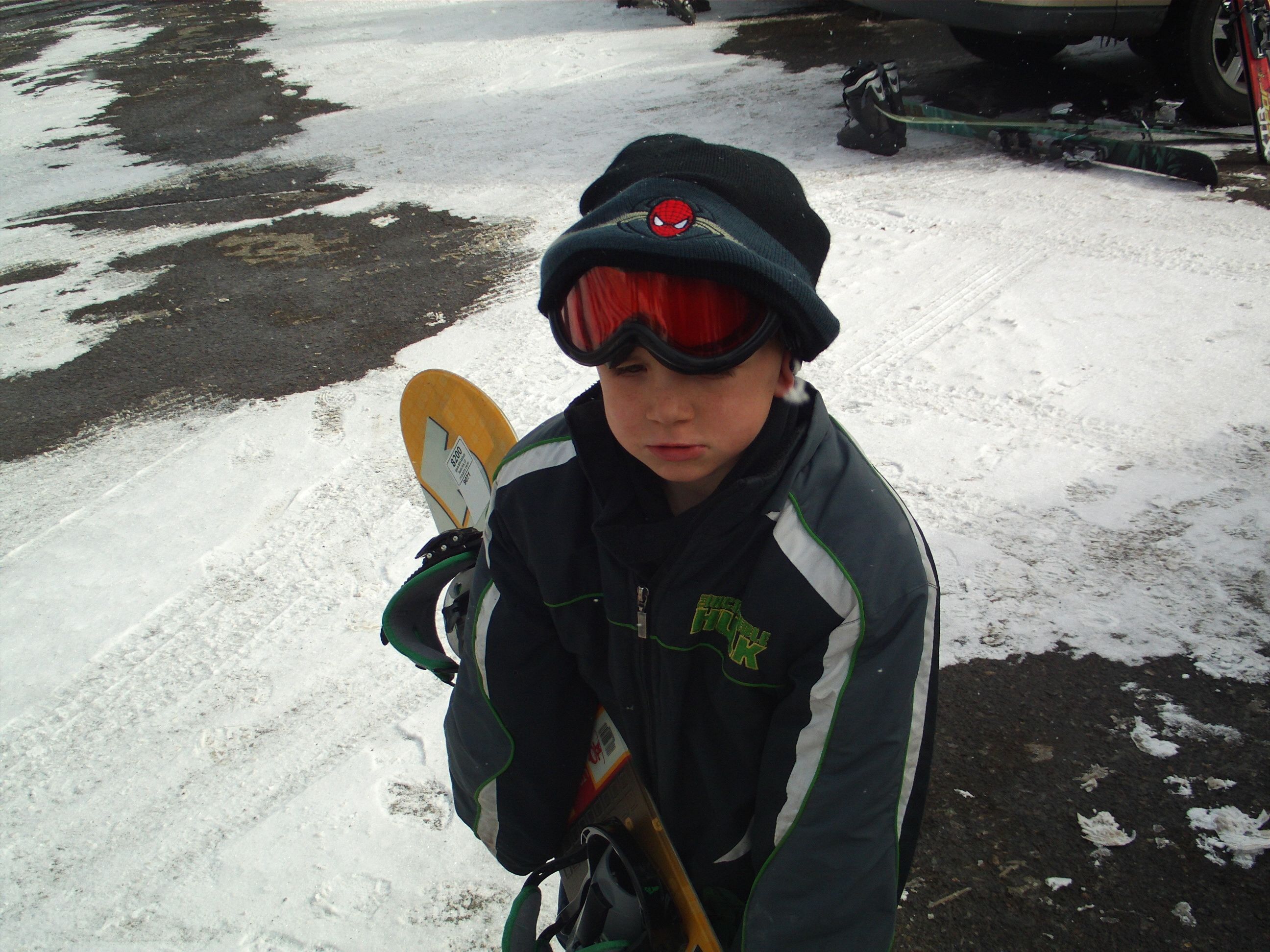 Una persona sosteniendo una tabla de snowboard, usando casco y una chaqueta.