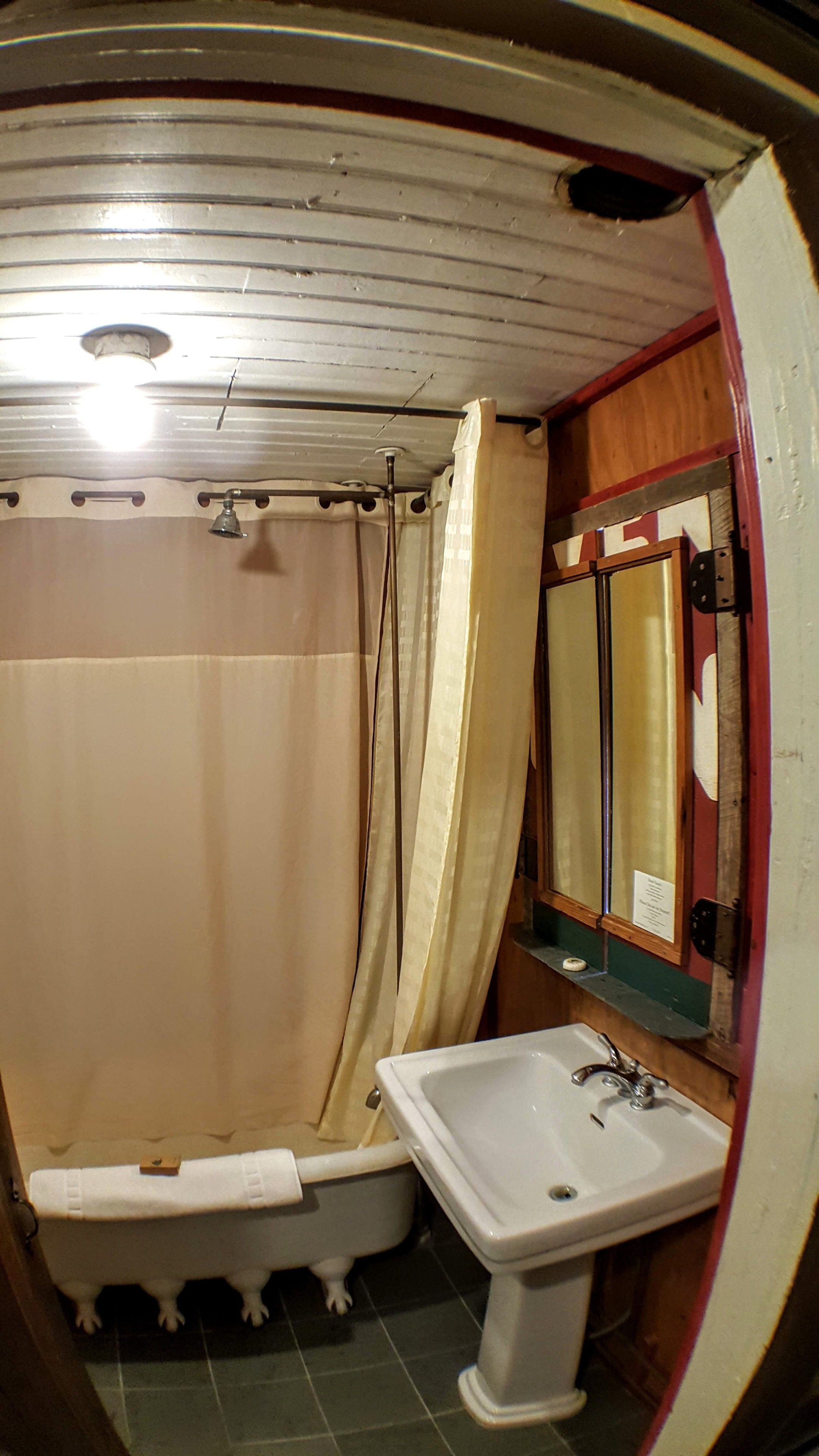 A bathroom with a bathtub, a sink, a mirror, and a shower curtain.