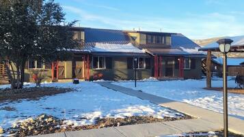 A modern building with a metal roof, a stone pathway, and a snow-covered ground.