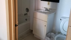 A small bathroom with a bathtub, a sink, a mirror, and a toilet.