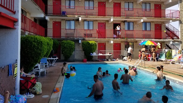 A hotel with multiple balconies, a swimming pool, and outdoor seating areas.