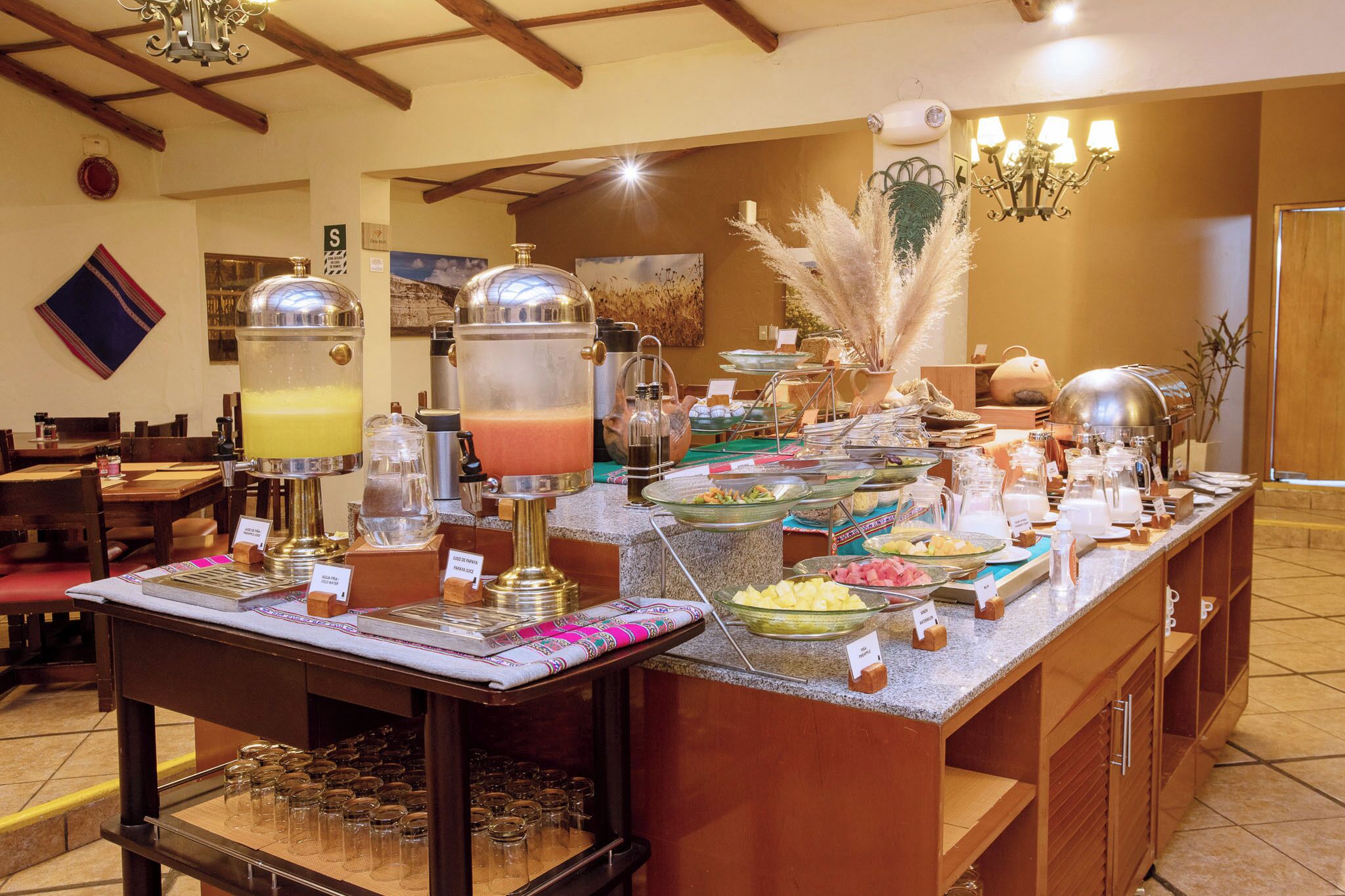 A buffet area with various food stations, including a fruit display and a beverage station with a large pitcher.