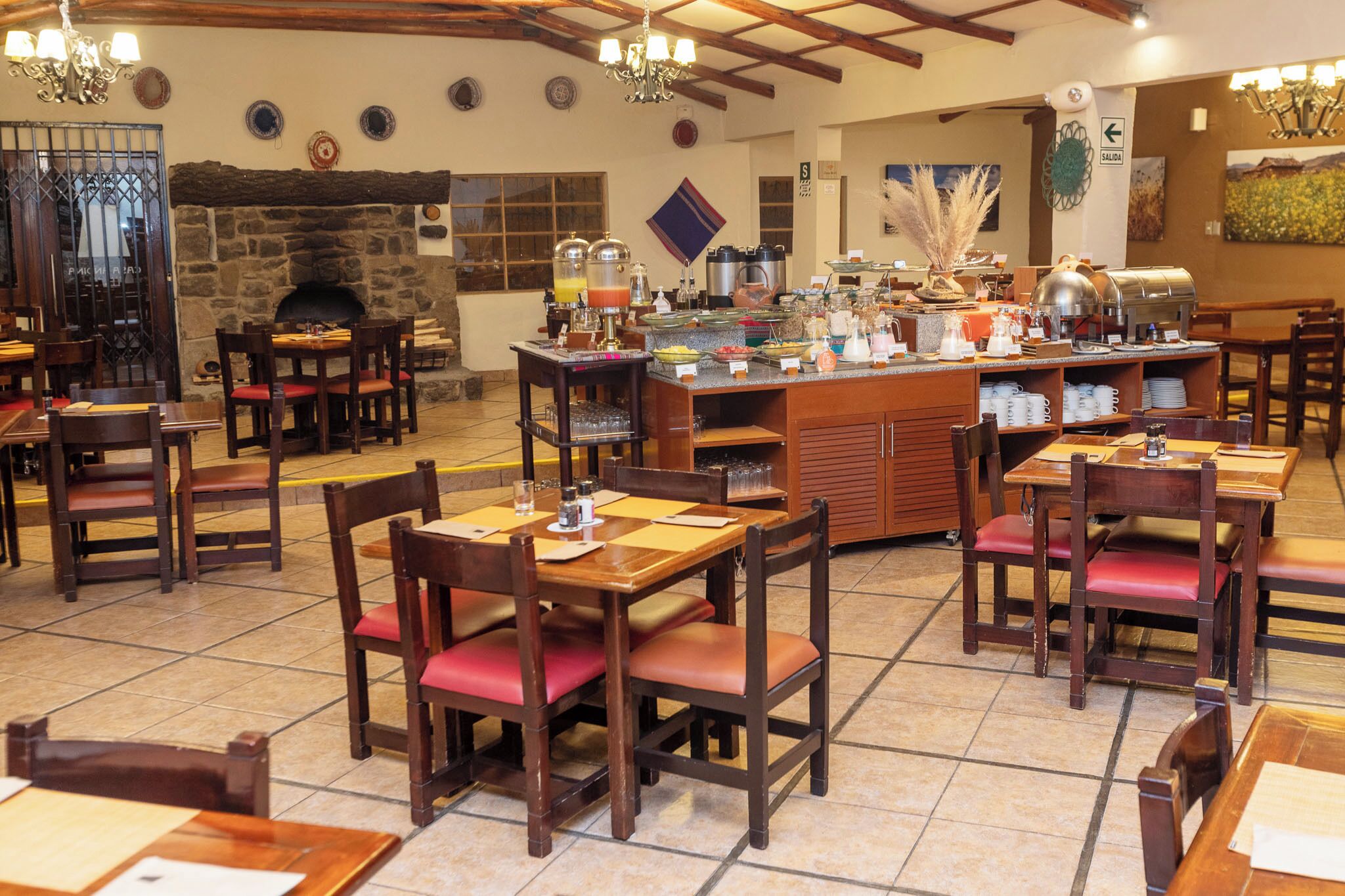 A restaurant with wooden tables and chairs, a buffet area, and a stone fireplace.