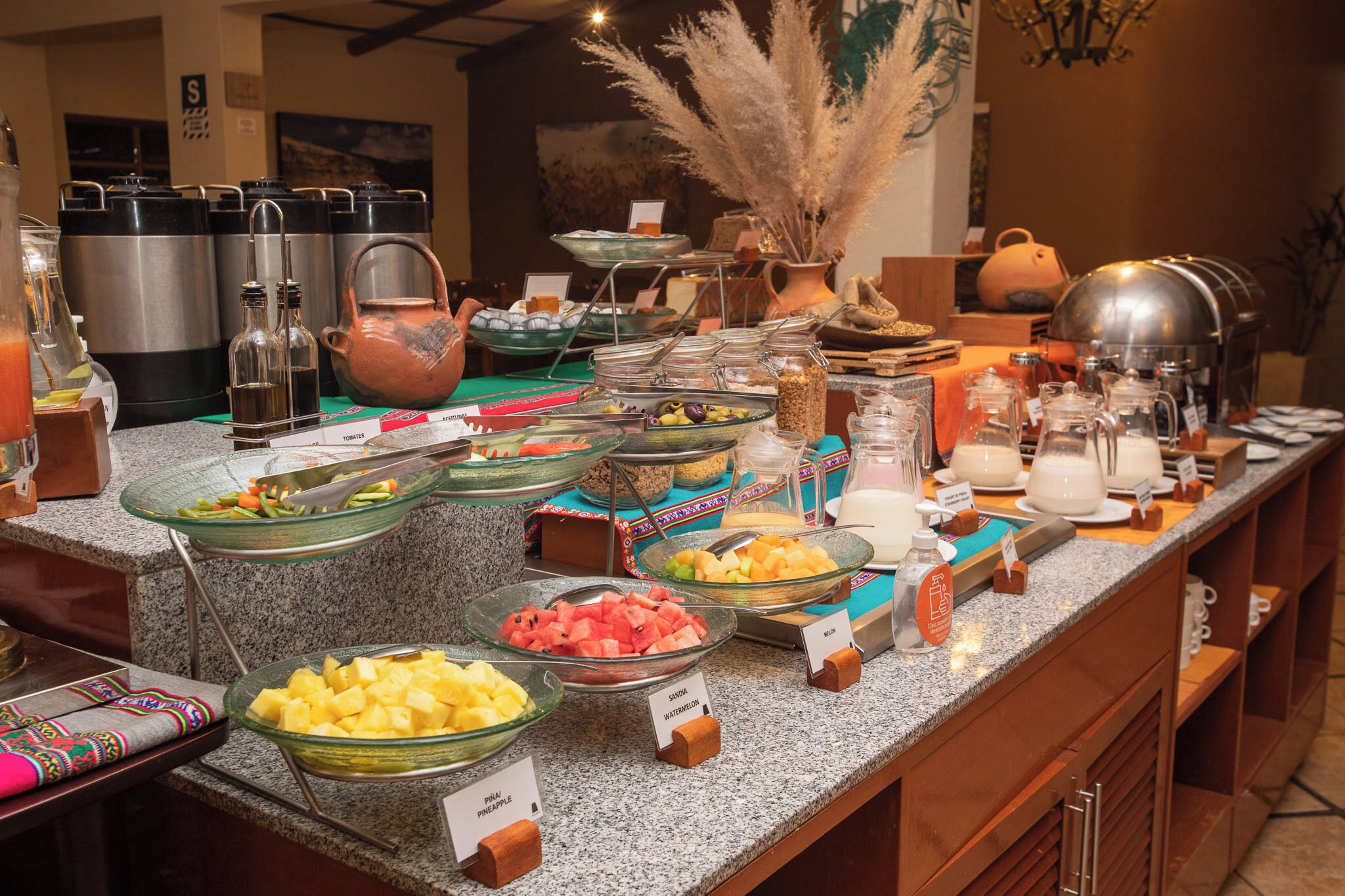 Un buffet proposant une variété de plats et de boissons, notamment des saladiers de fruits et un coin café.