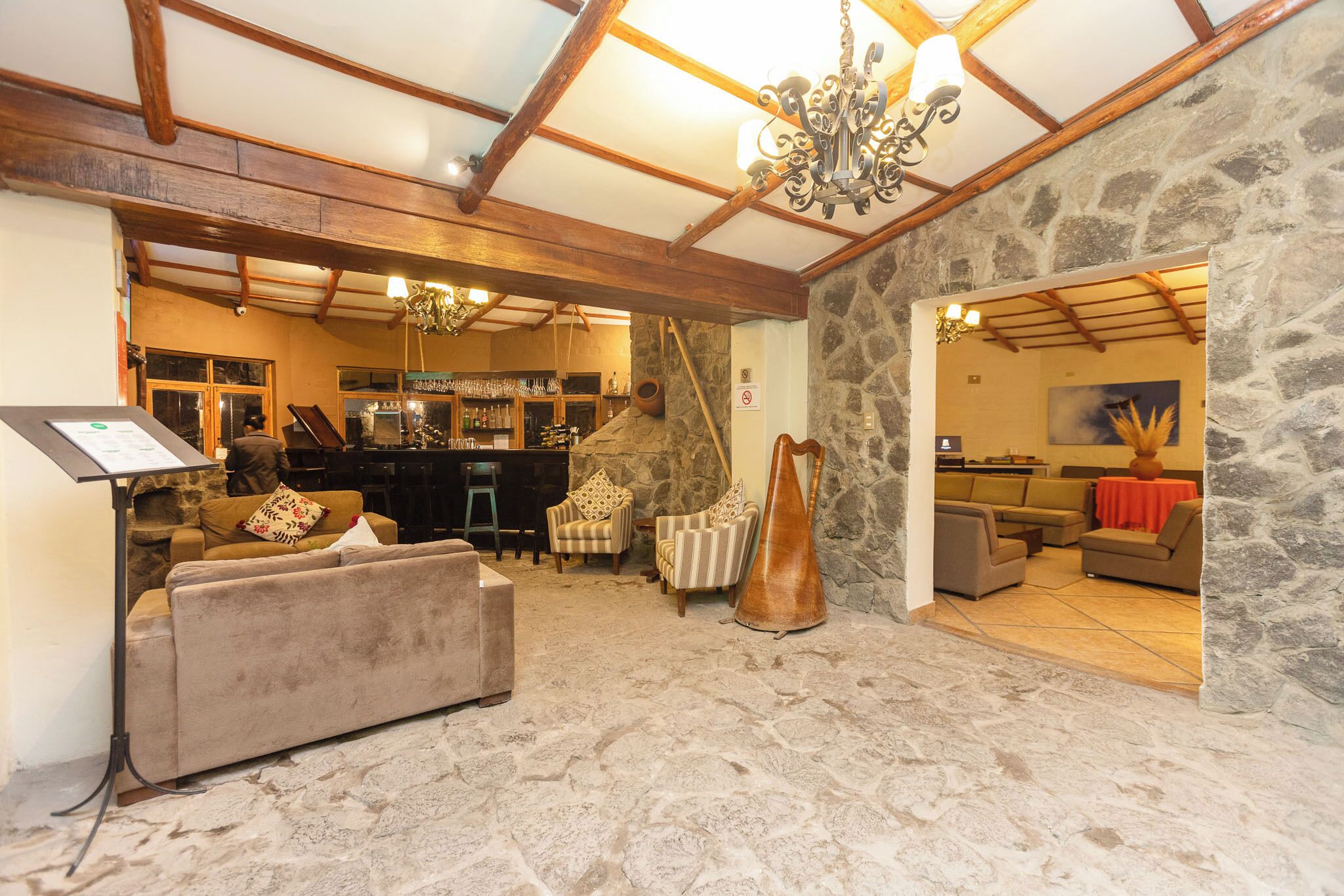 A spacious living area with a stone wall, a piano, and a bar area in the background.