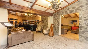 A spacious living area with a stone wall, a piano, and a bar area in the background.