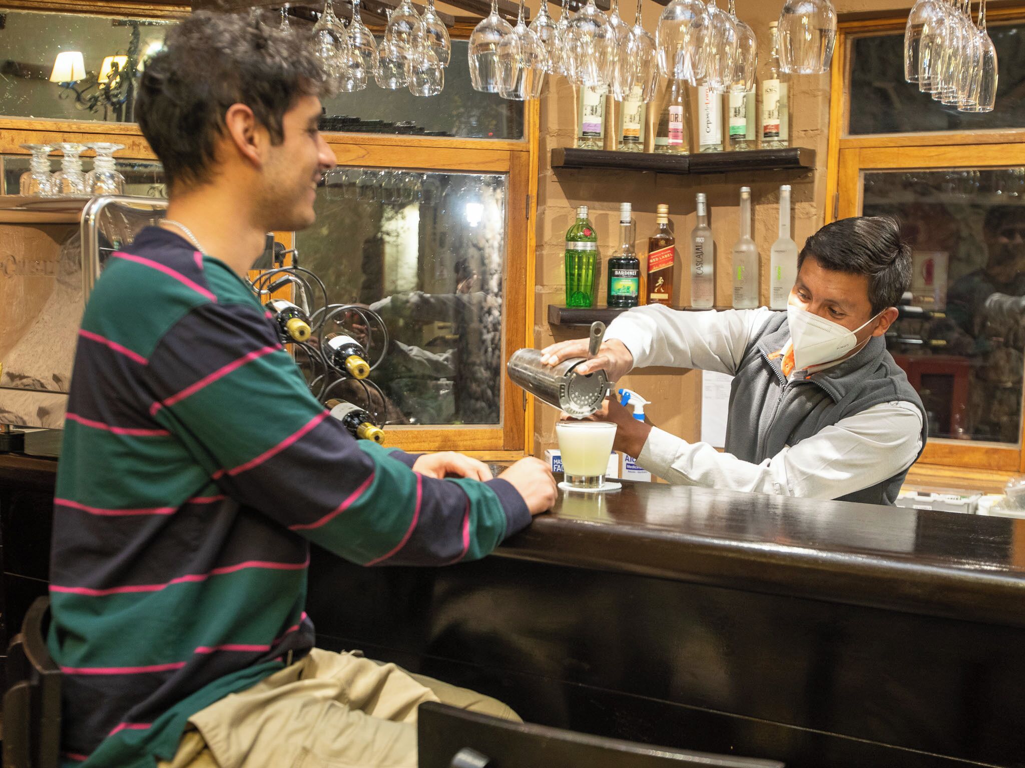 A bar setting with a bartender preparing a drink.