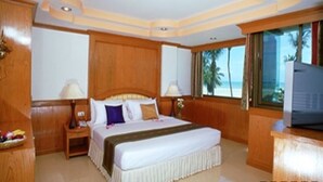 A hotel room with a large bed, wooden paneling, a TV, and a view of the ocean. - Grand Sea View Resotel (Koh Samui)