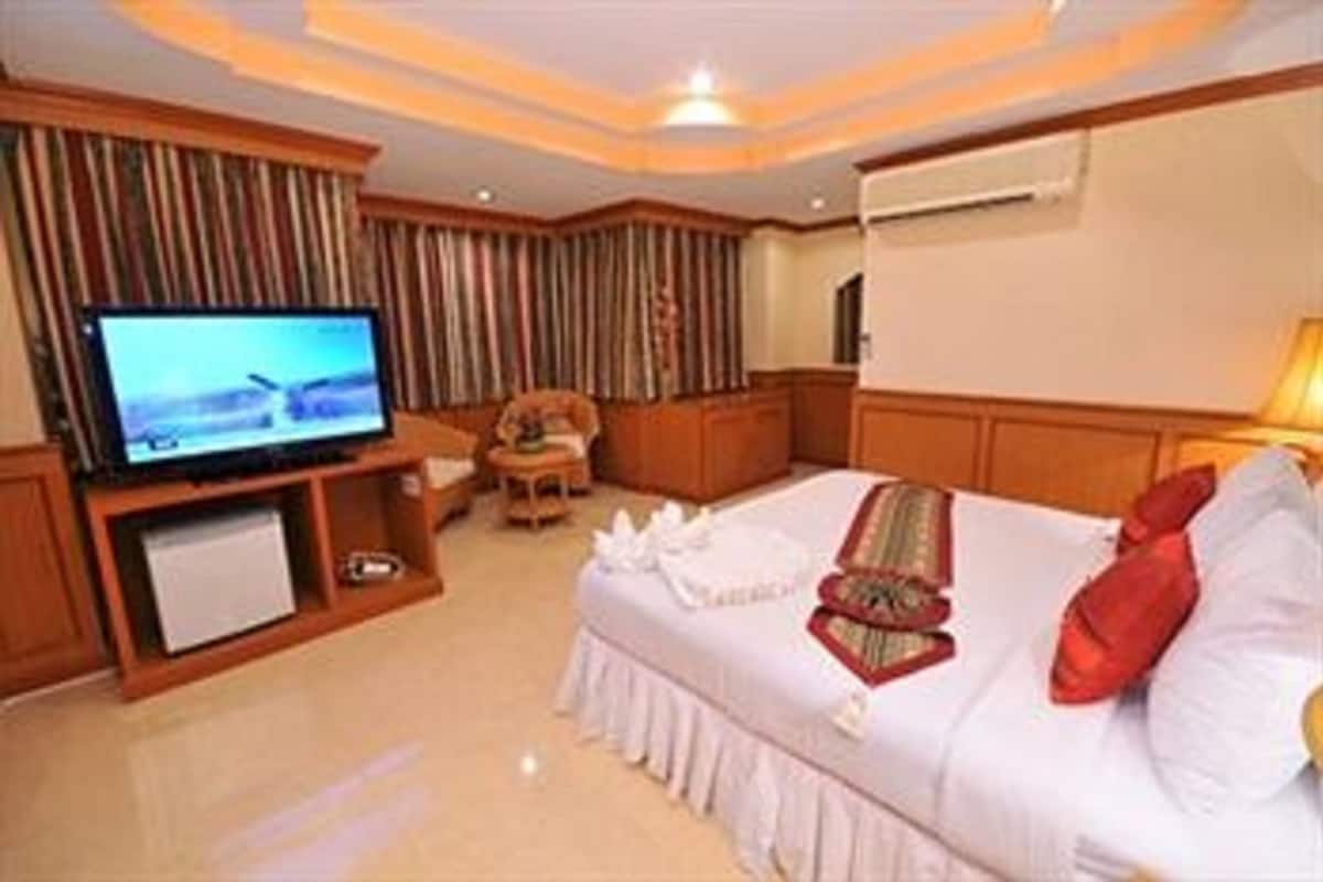 A hotel room with a television, a sofa, a small table, and a bed.