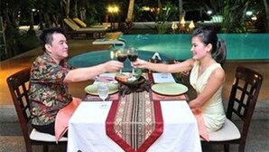 A dining table with a white tablecloth and a red centerpiece, surrounded by chairs. - Grand Sea View Resotel (Koh Samui)