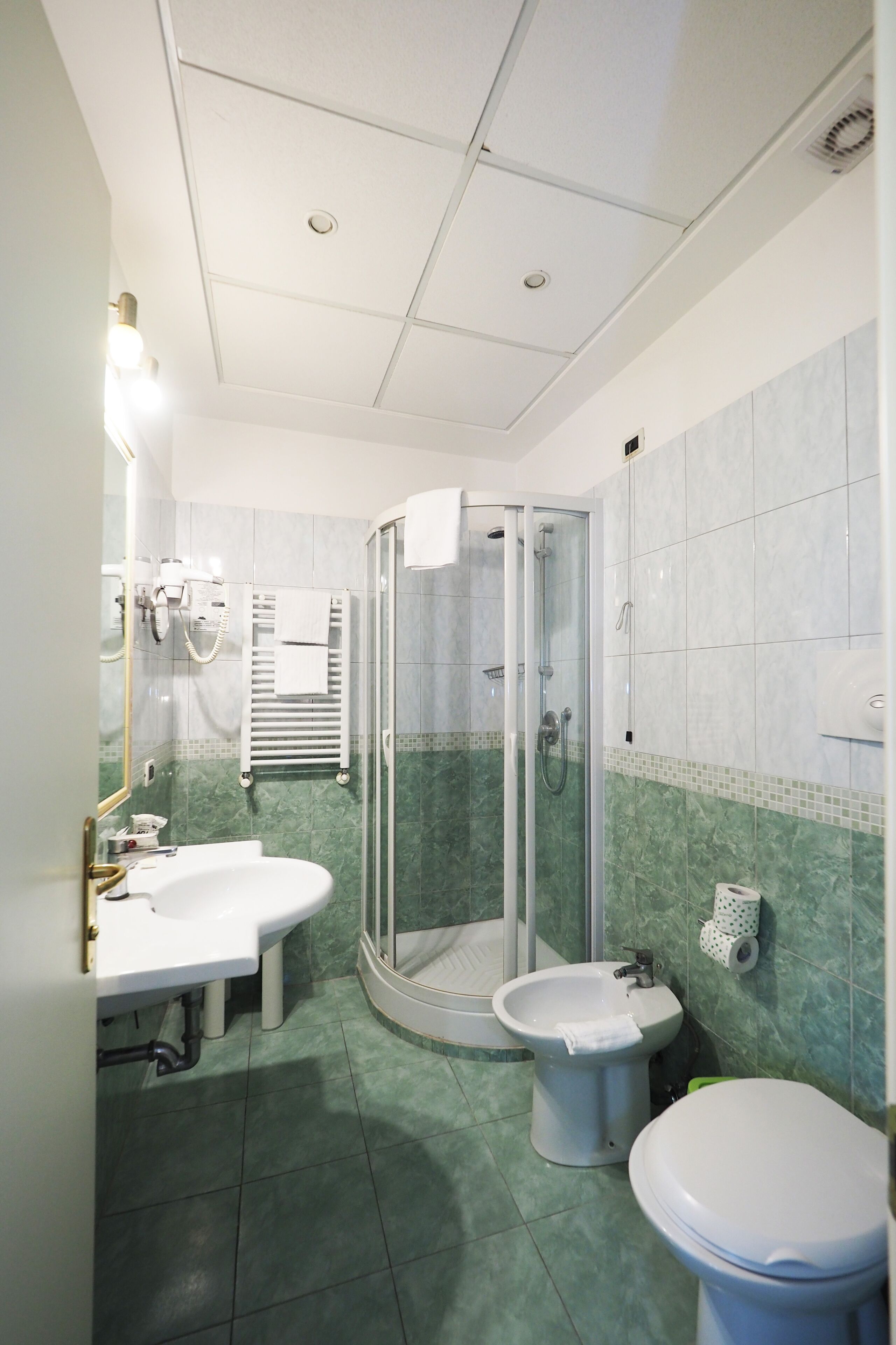 Een badkamer met douche, toilet, bidet en wastafel.