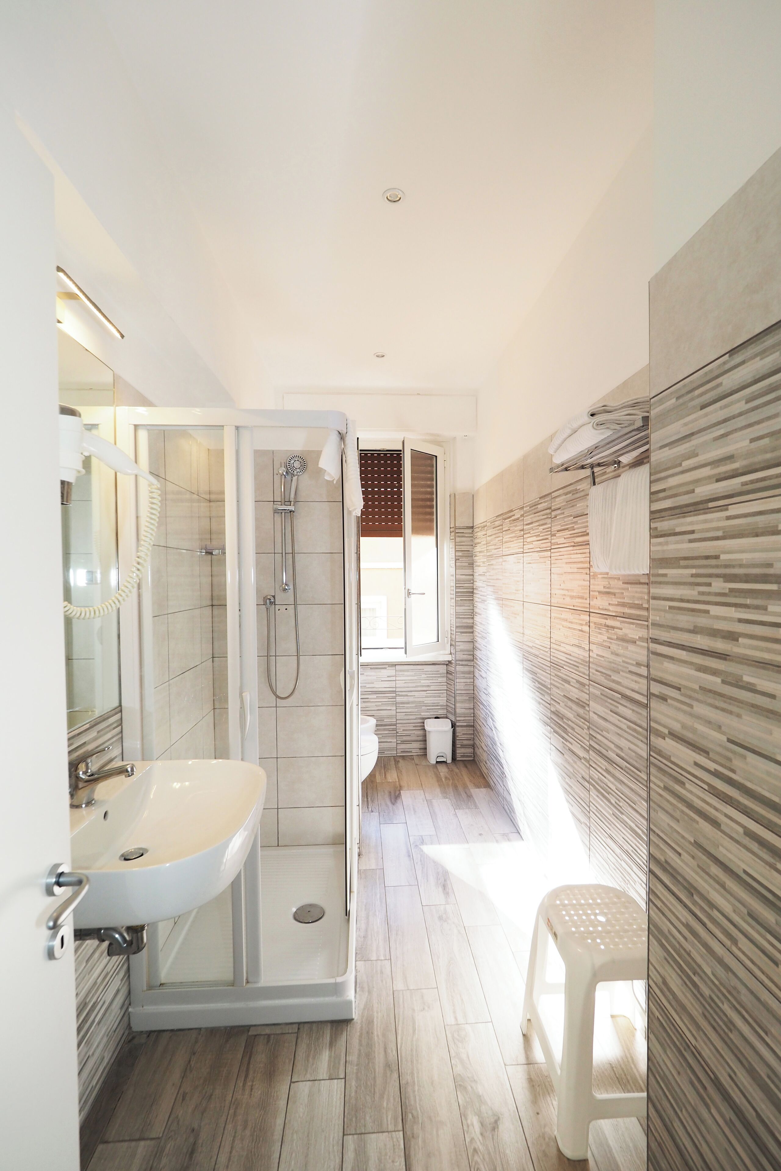 A modern bathroom with a glass-enclosed shower, a sink, and a toilet.