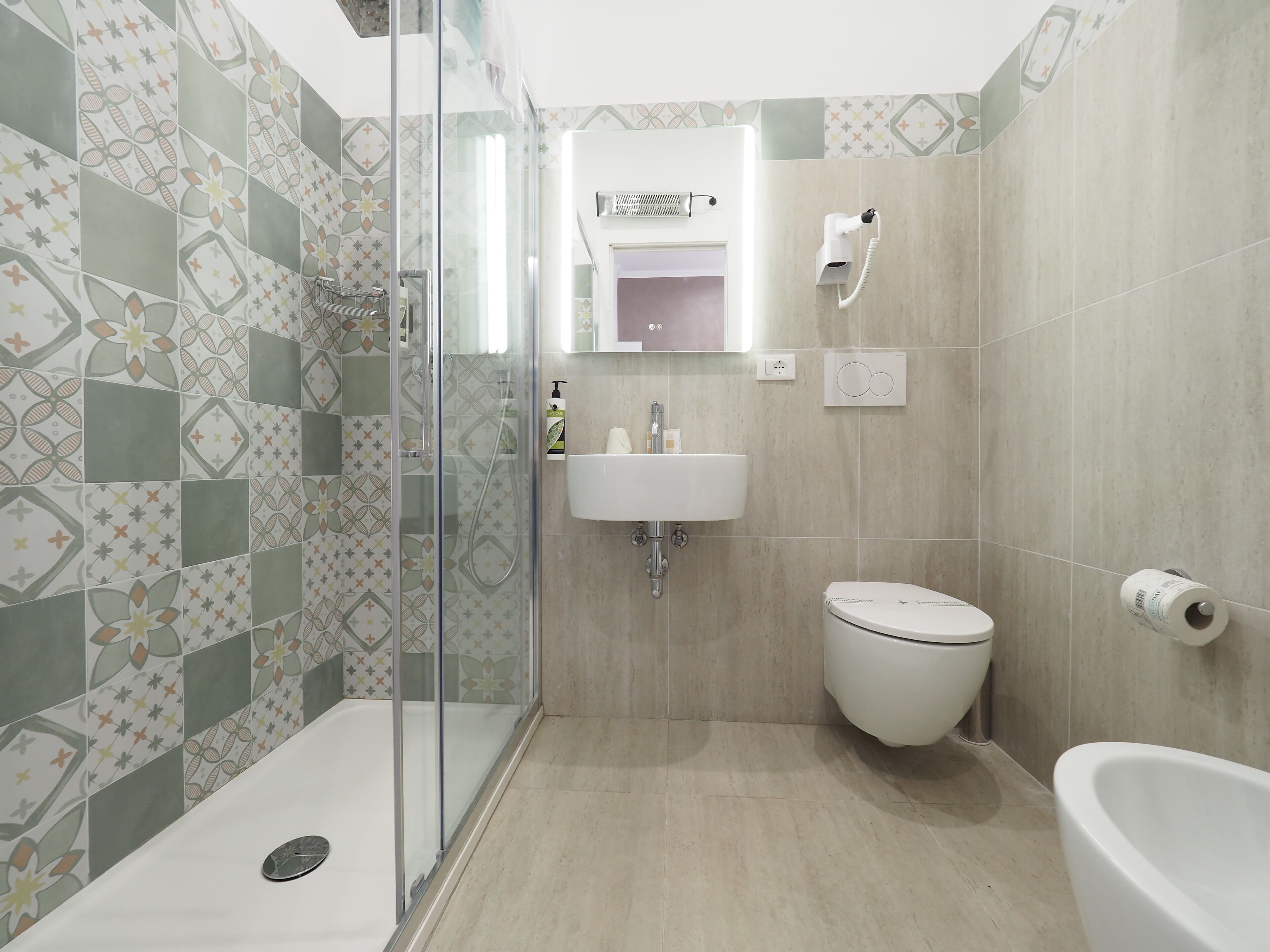 Ein Badezimmer mit Dusche, Toilette, Waschbecken und einer Duschkabine aus Glas.
