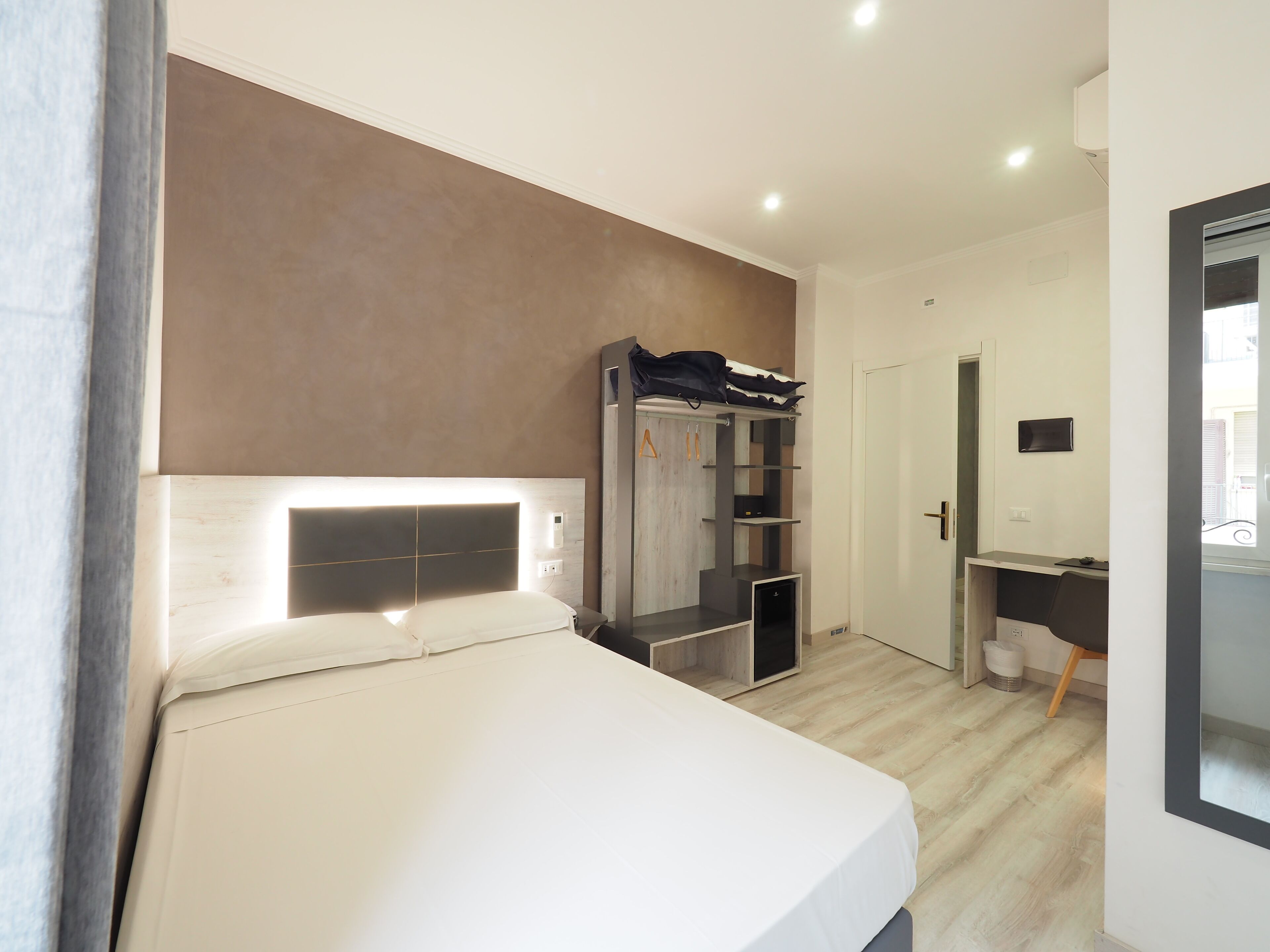 Un dormitorio moderno con cama, armario y zona de escritorio.