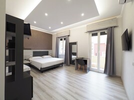 Moderni hotellihuone, jossa on suuri sänky, työpöytä ja televisio.