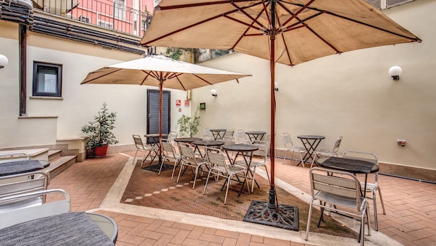 An outdoor patio with tables and chairs, umbrellas, and a potted plant. - Hotel Osimar (Rome)