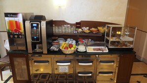 A breakfast bar with a coffee machine, a juice dispenser, and various food items. - Hotel Osimar (Rome)
