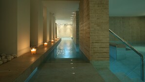 Un pasillo tipo spa con un estanque reflectante, velas y una escalera.