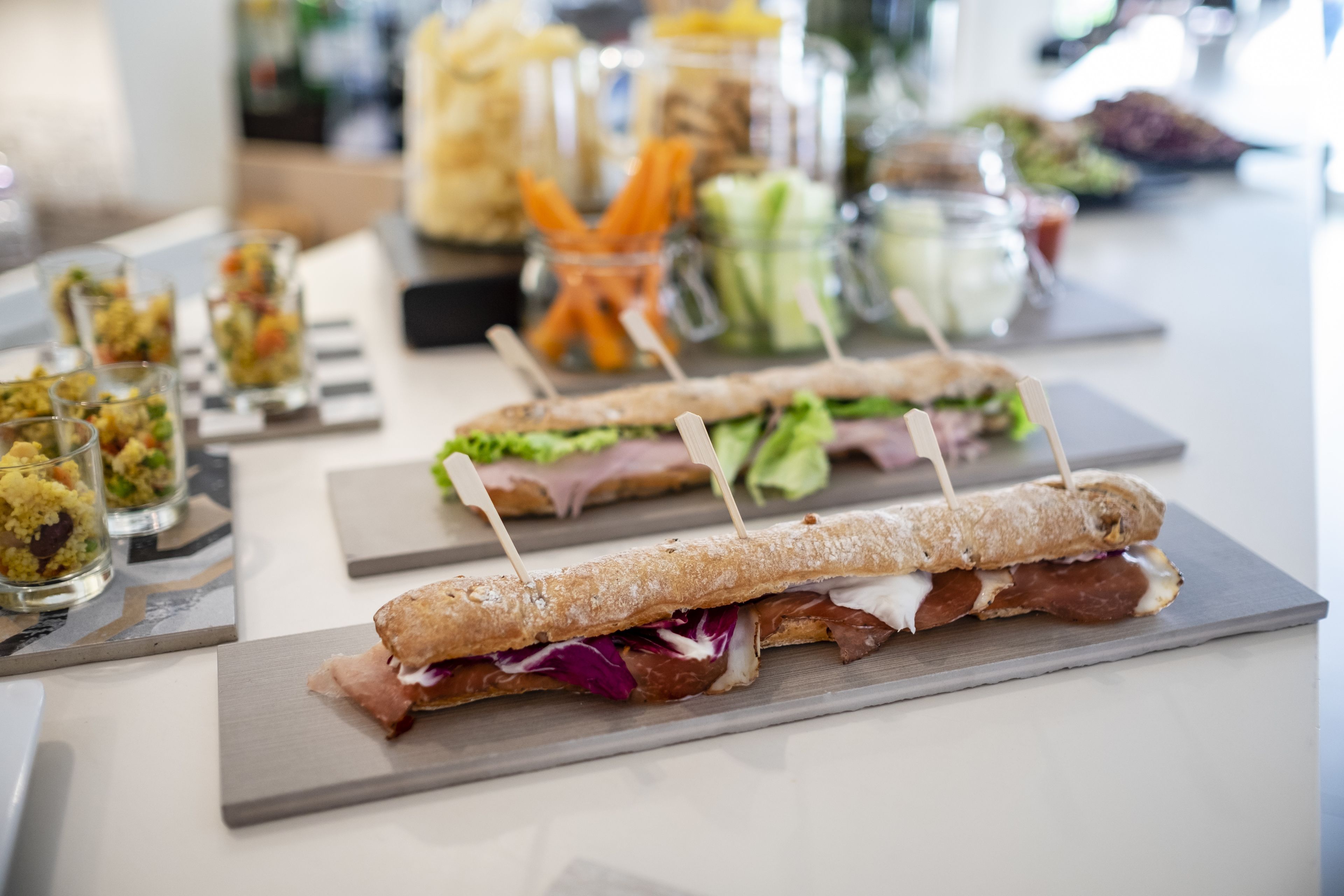 Un tavolo da buffet con diversi cibi, tra cui panini, insalate e bevande.