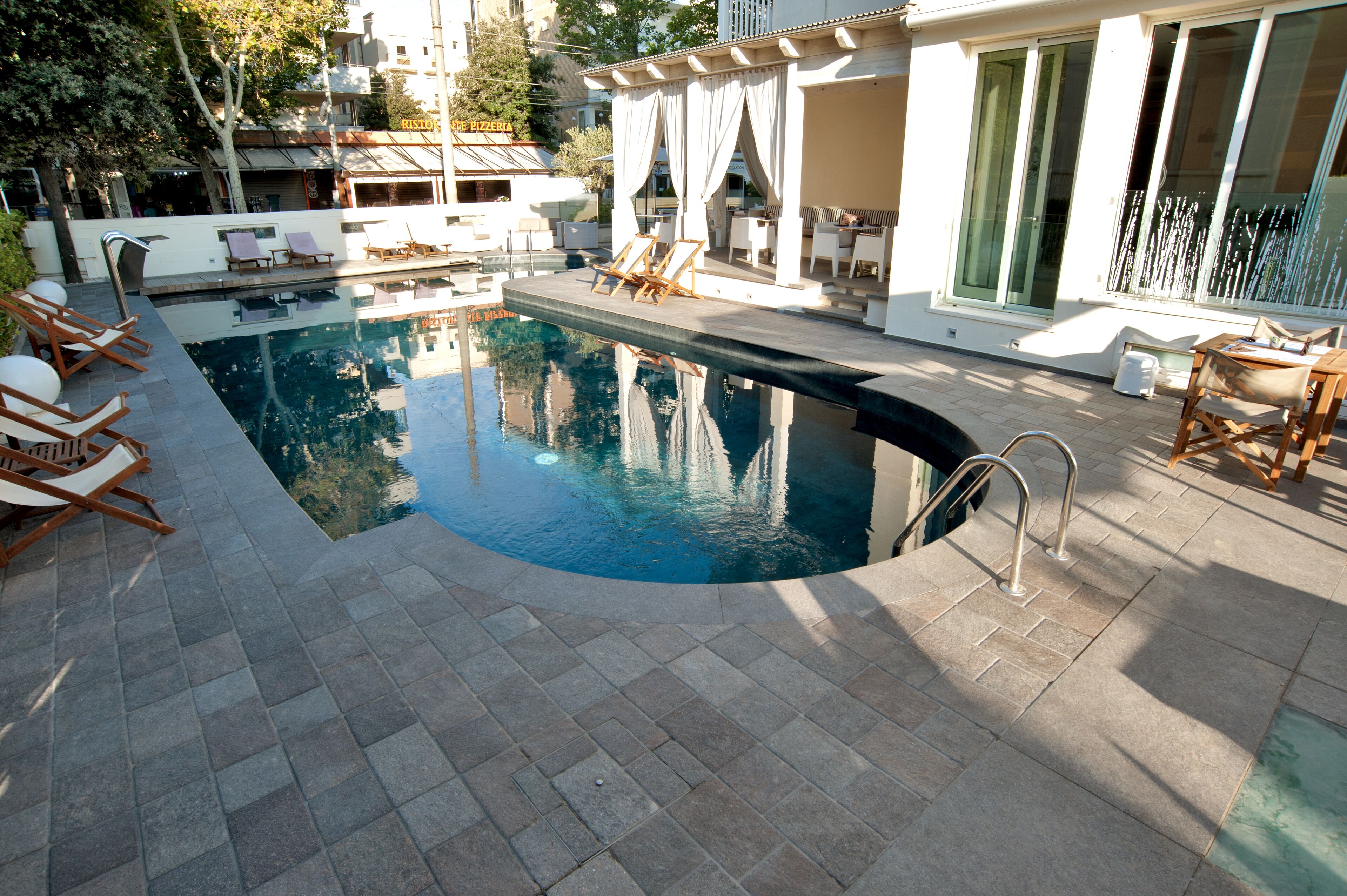 Une piscine avec des chaises longues et un espace de détente abrité.