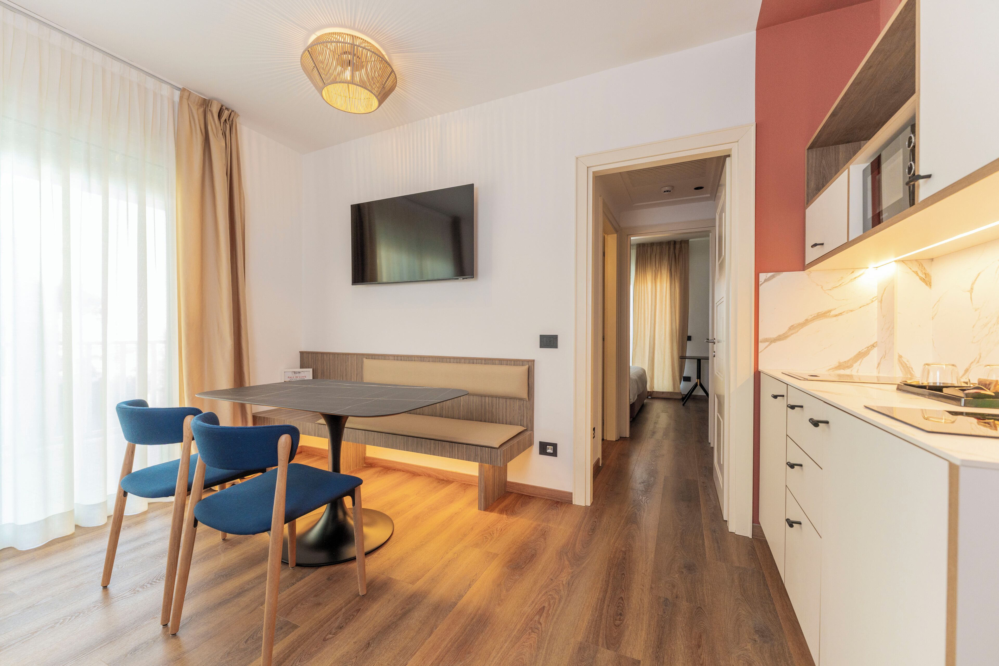 Una camera d'albergo moderna con zona pranzo, televisione e angolo cottura.
