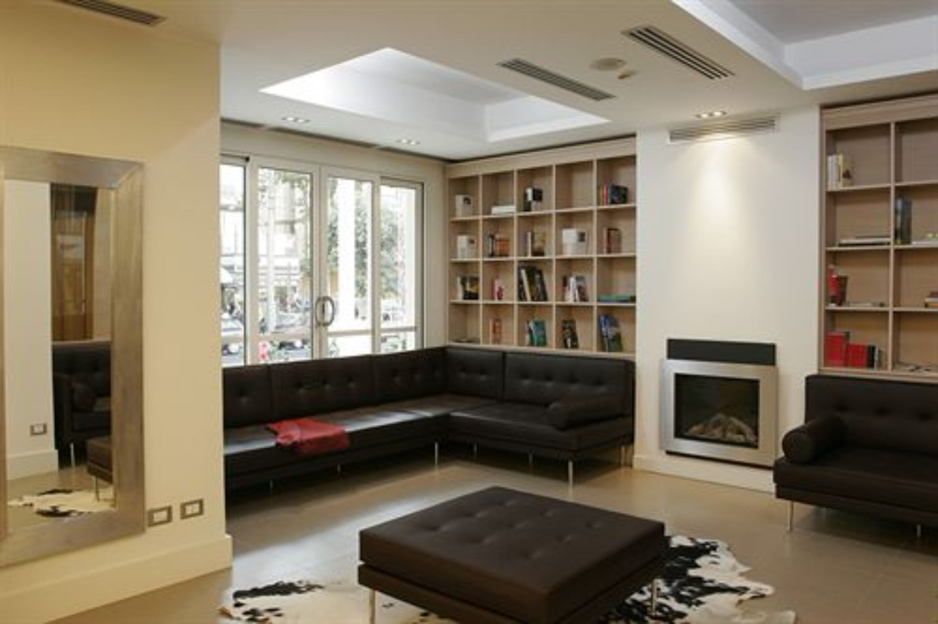 A modern living room with a sectional sofa, a fireplace, and built-in bookshelves.