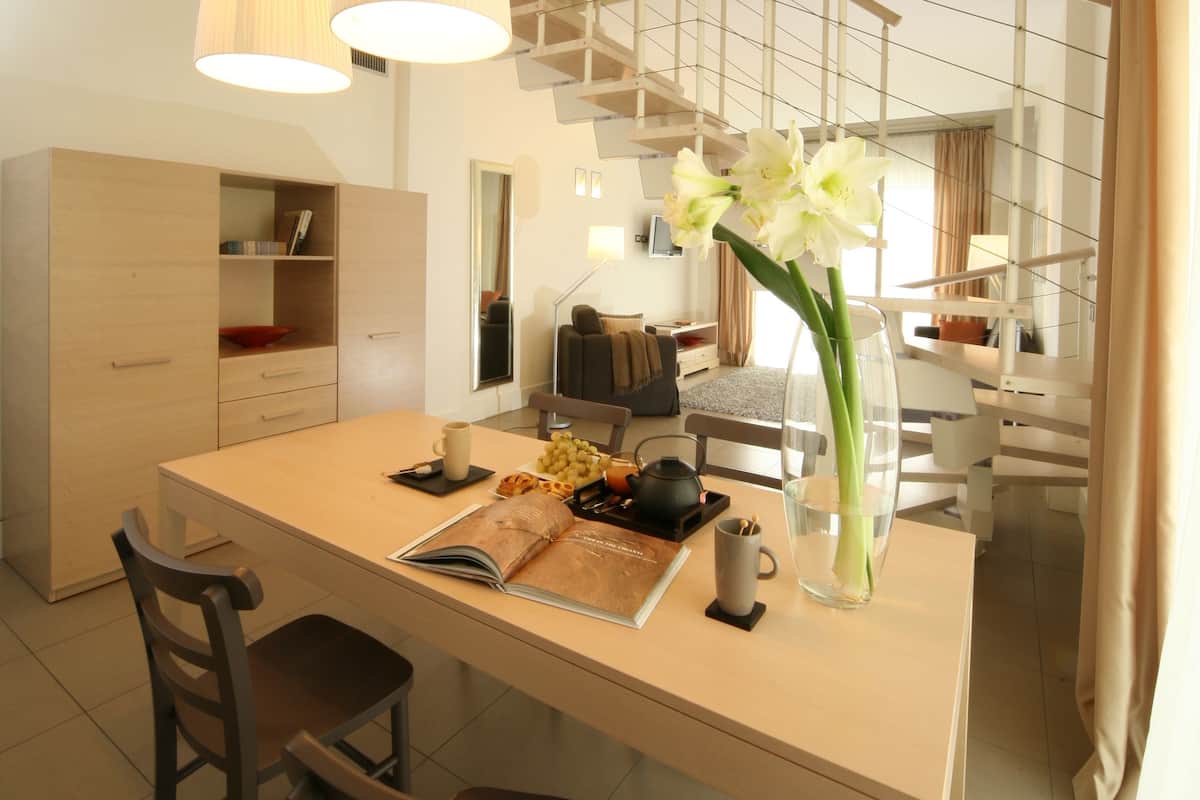 A modern kitchen with a central island, two pendant lights, and a vase with flowers.