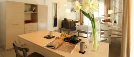 A modern kitchen with a central island, two pendant lights, and a vase with flowers.