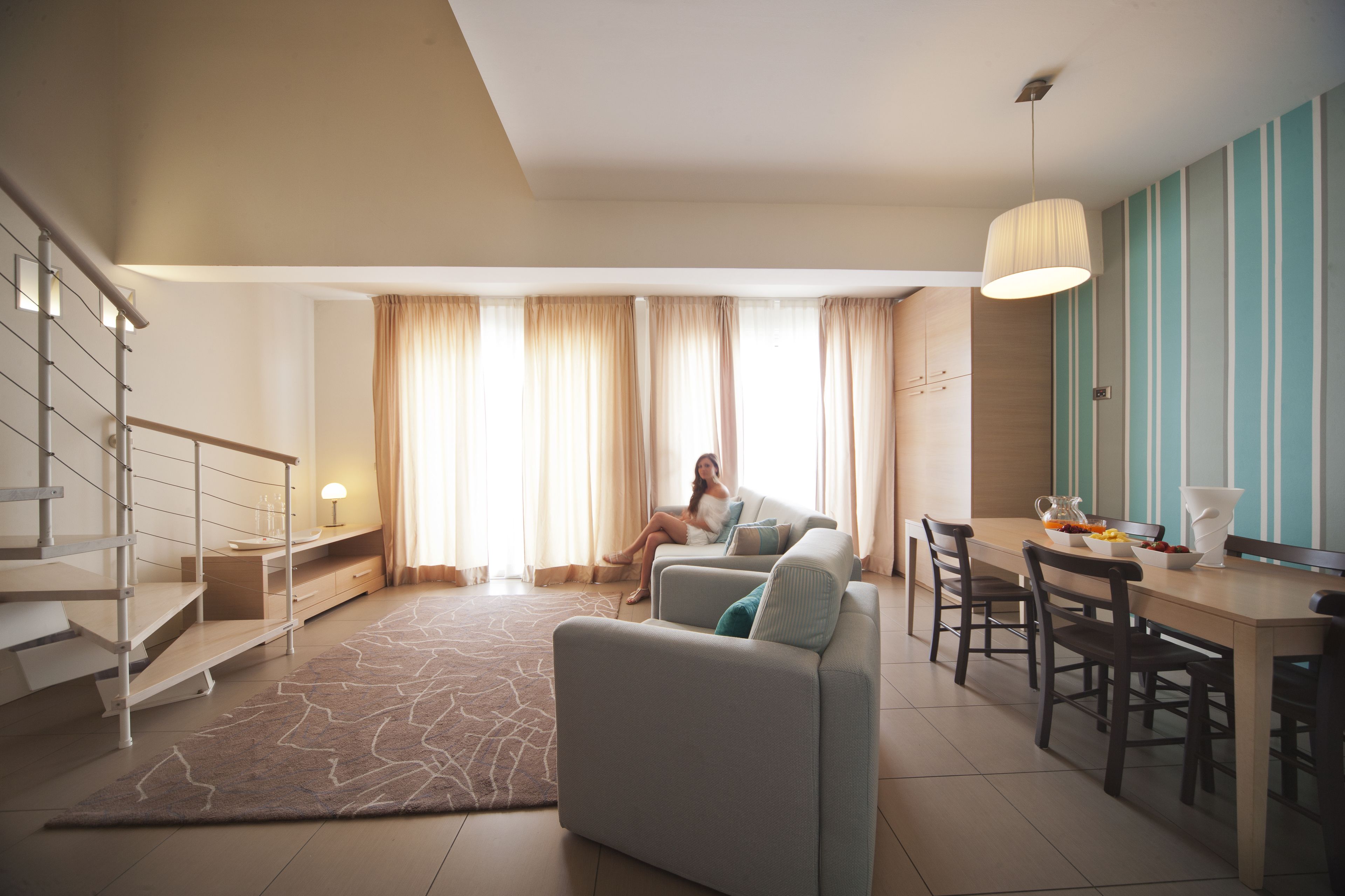 A modern living room with a sofa, dining table, and staircase.